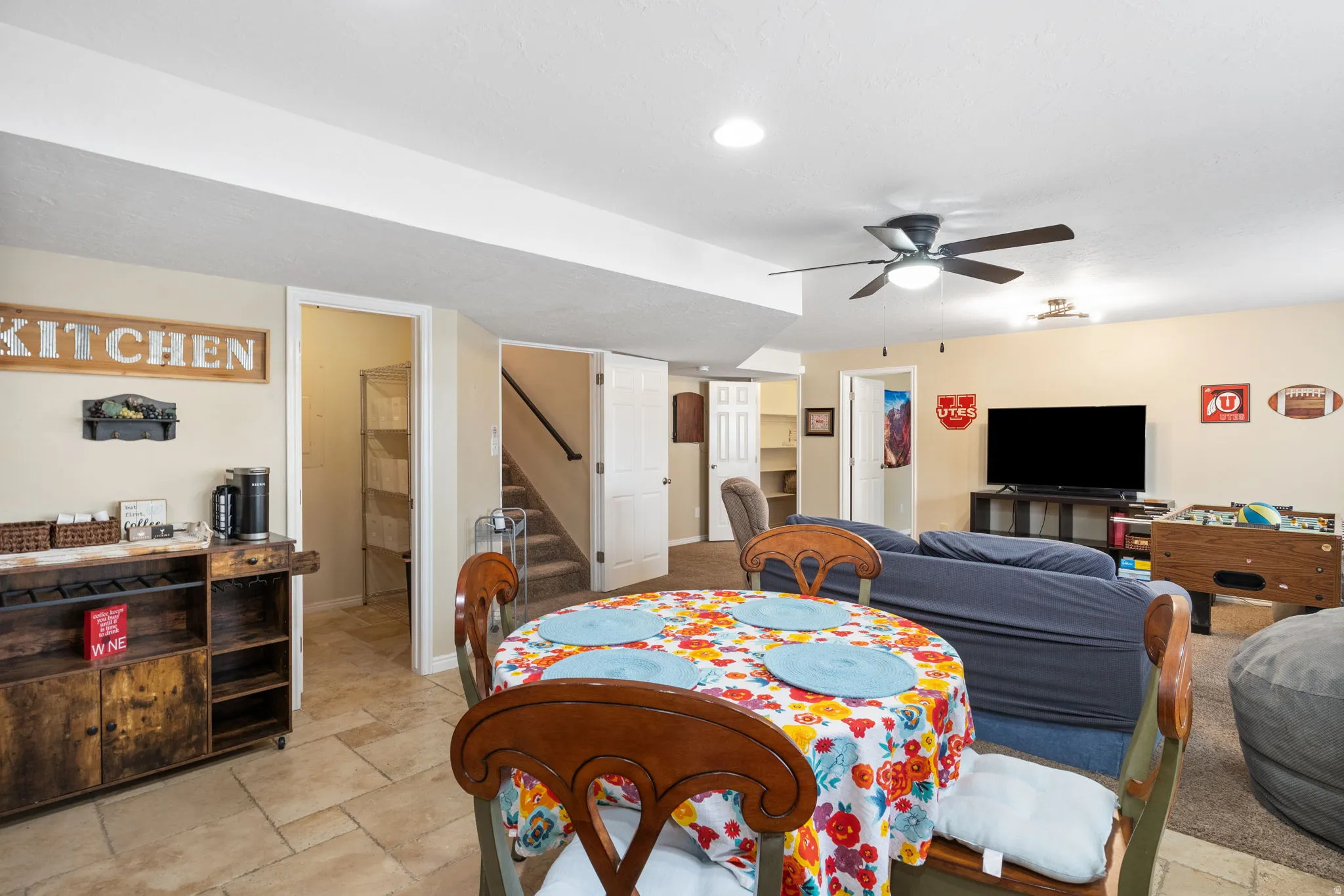 Dining room with stairs, a ceiling fan, and stone tile floors
