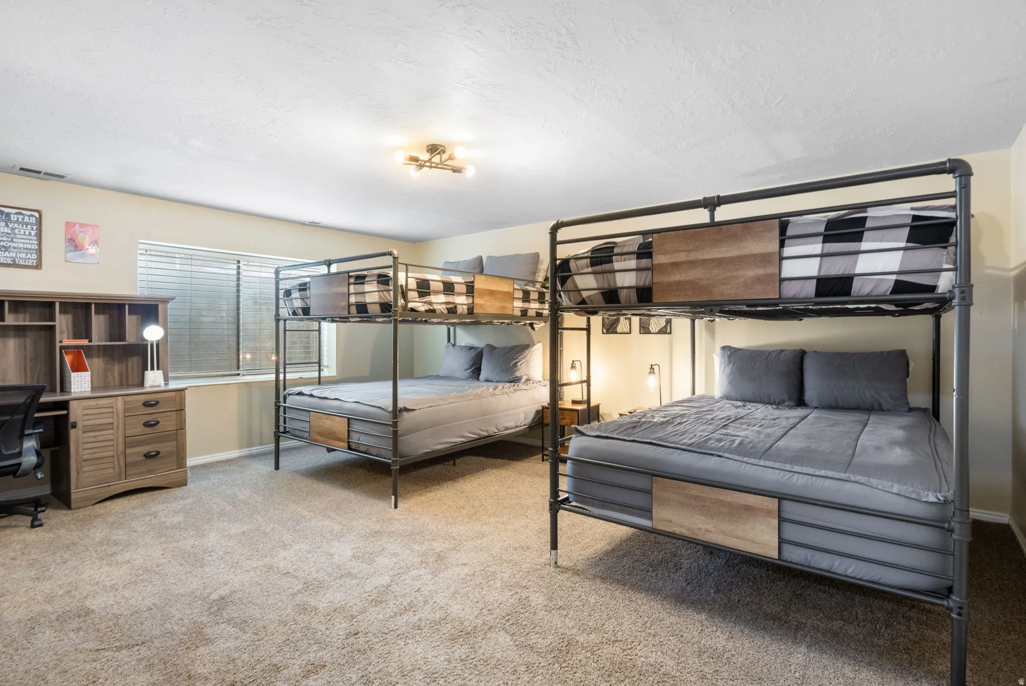 Bedroom with light carpet, a textured ceiling, and a desk