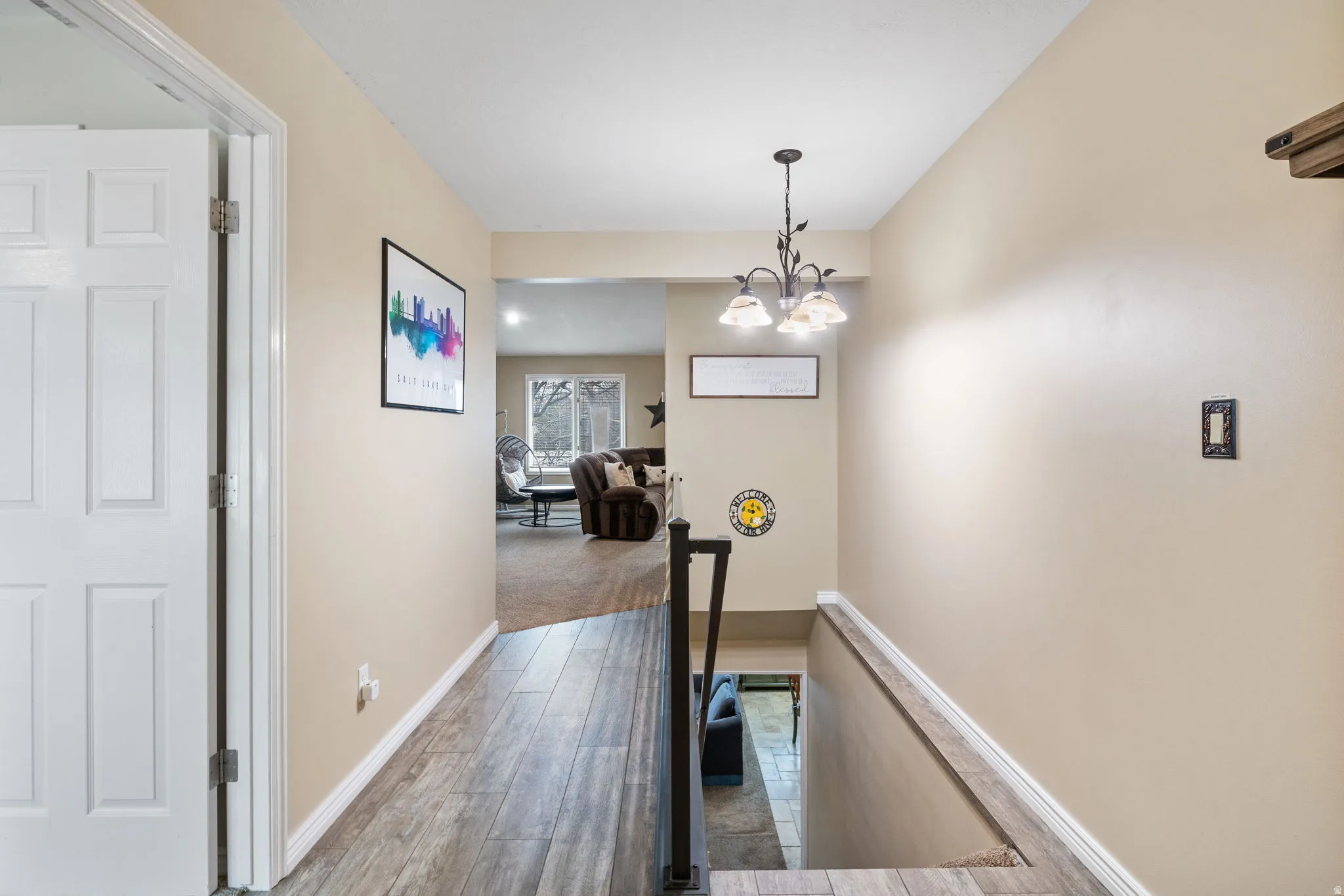 Corridor with an upstairs landing, a chandelier, and light wood-type flooring