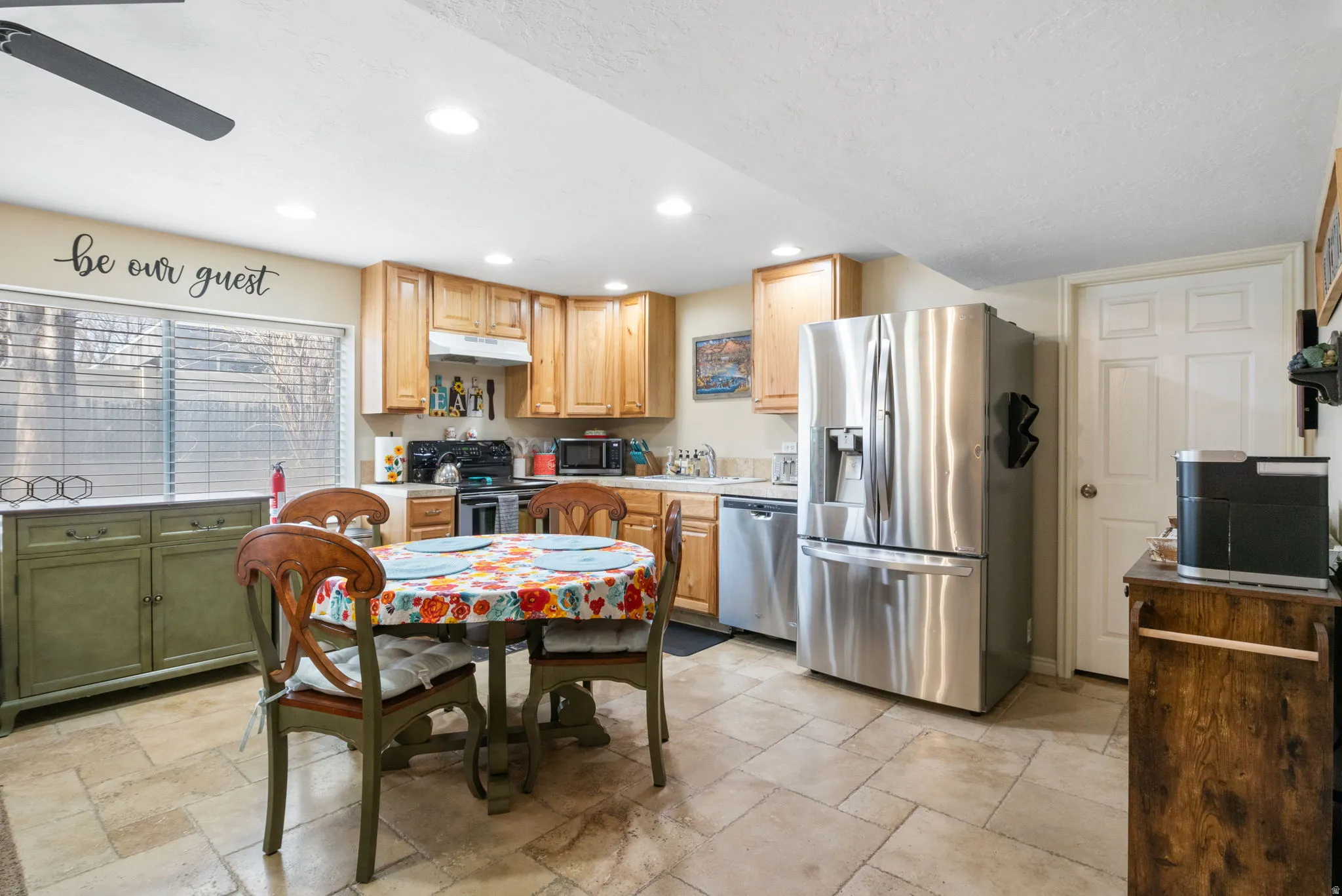 Kitchen with stainless steel appliances, light countertops, recessed lighting, stone tile floors, and under cabinet range hood