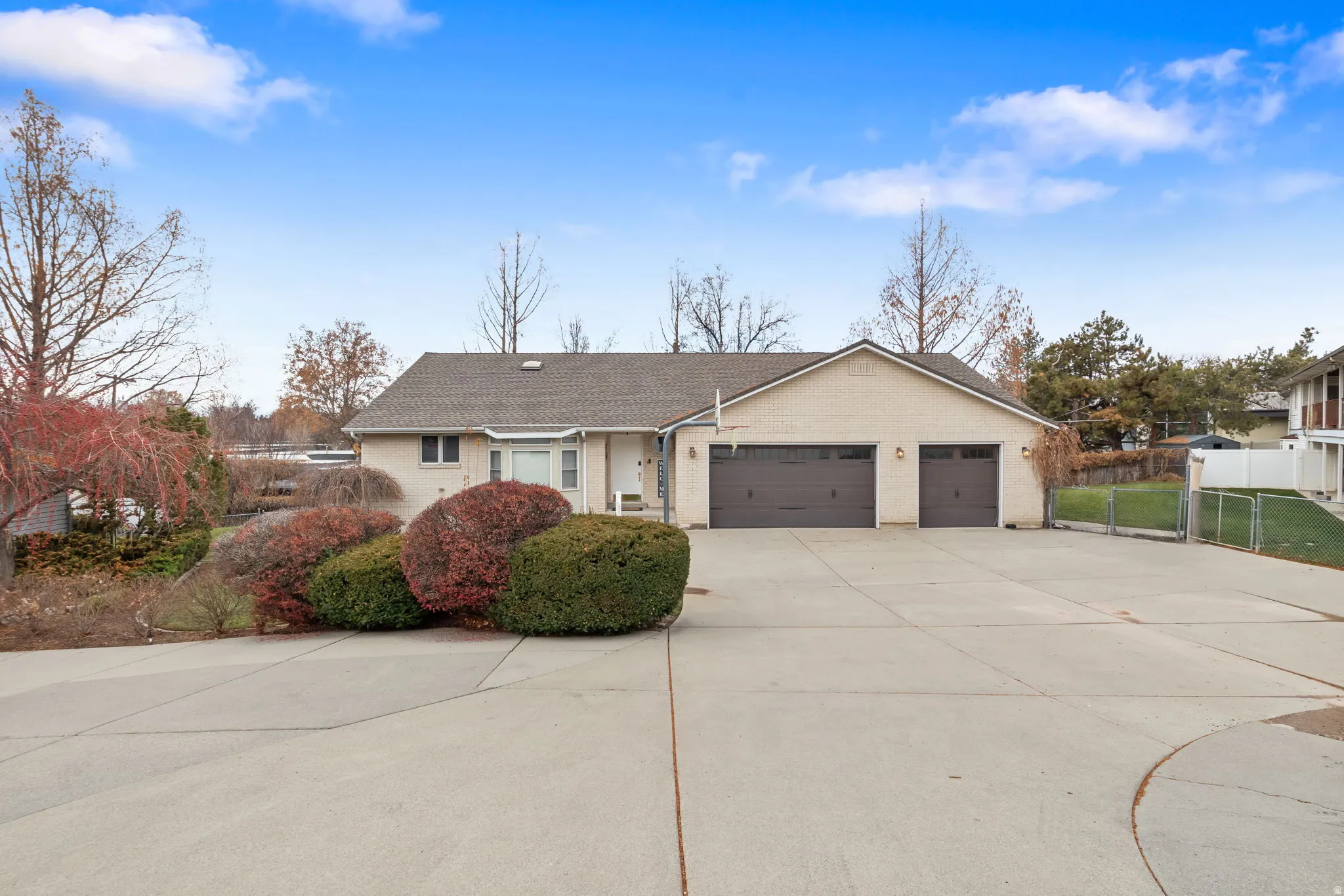 Ranch-style house with a garage, driveway, a shingled roof, and brick siding
