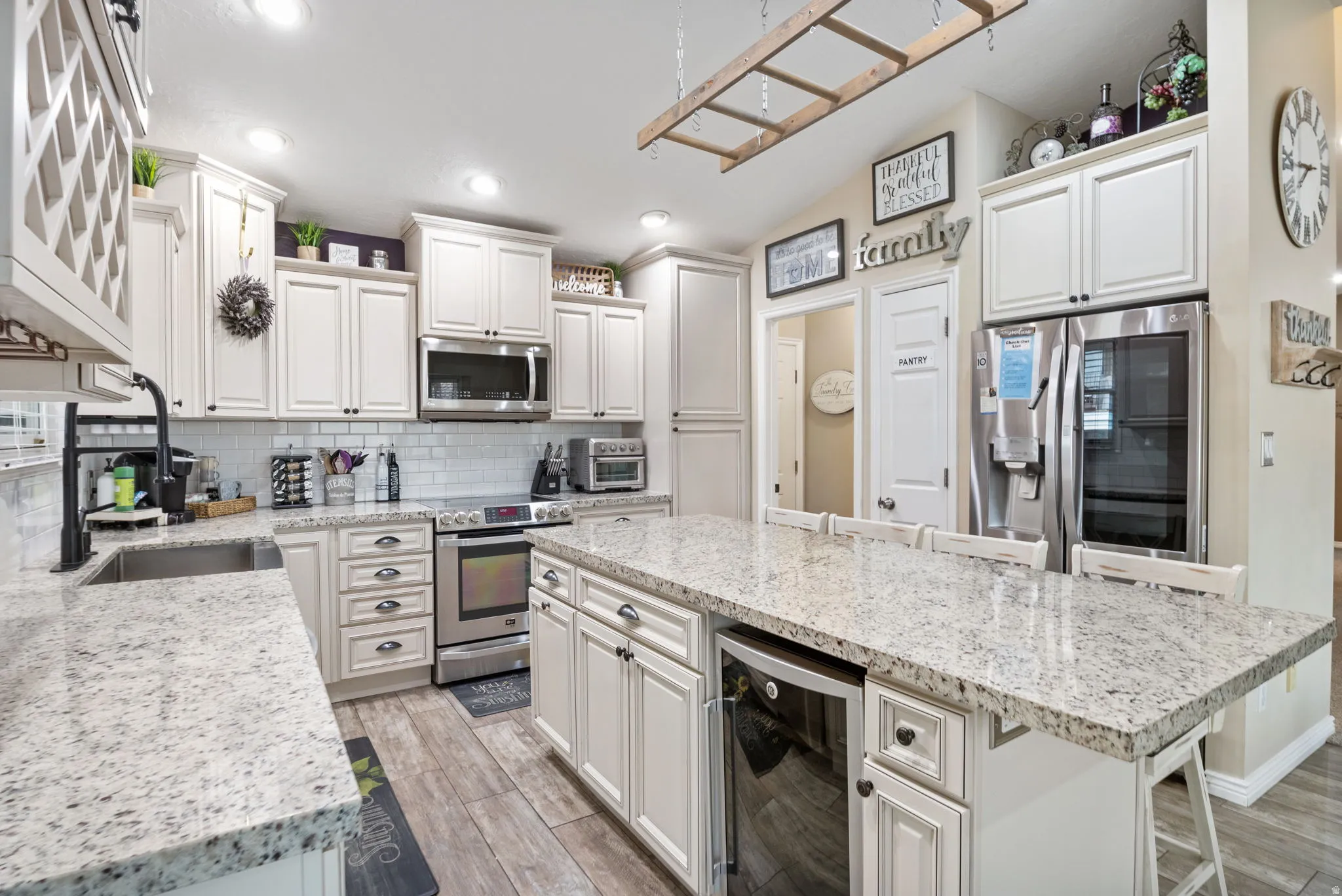 Kitchen featuring wine cooler, stainless steel appliances, light stone counters, a kitchen island, and recessed lighting