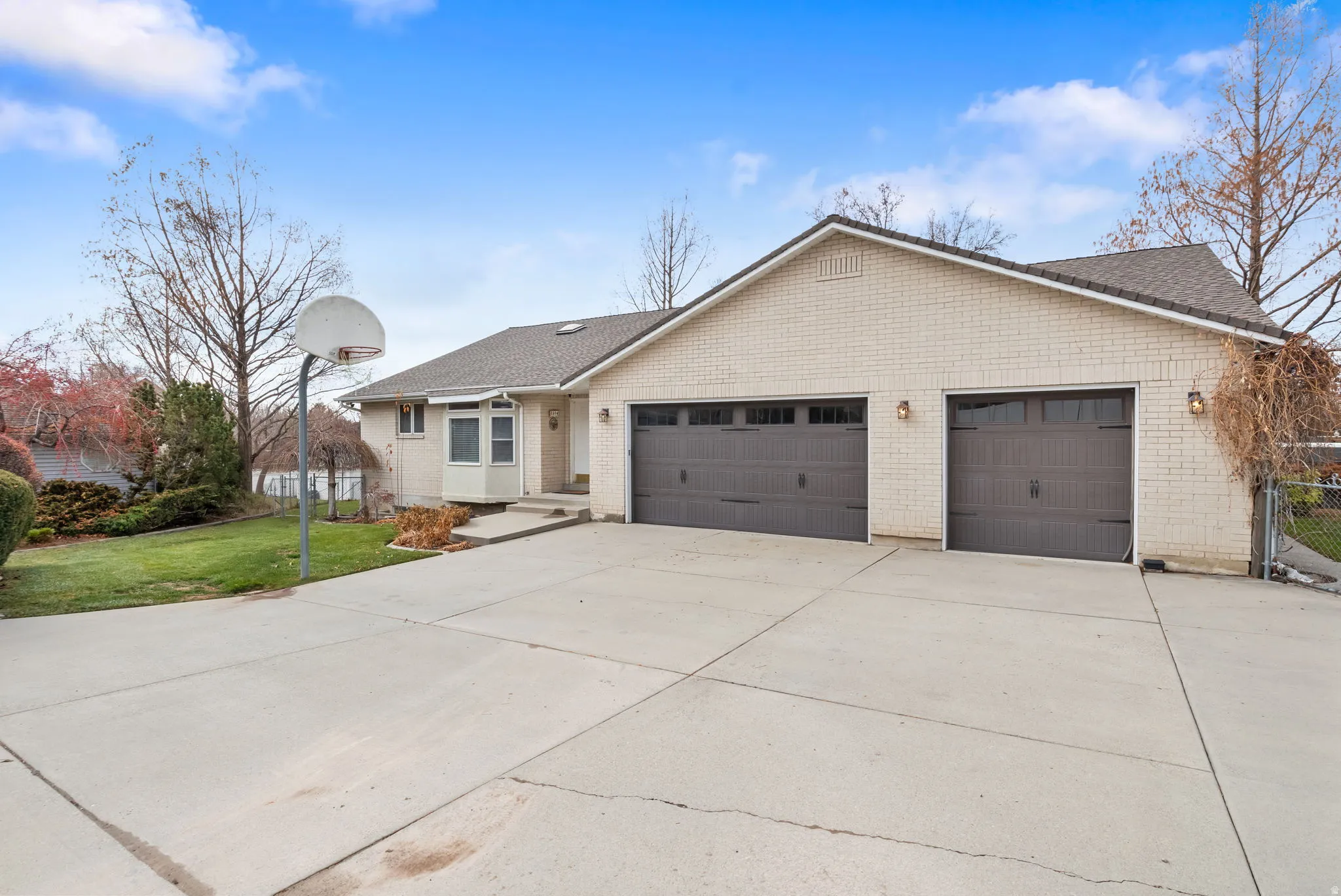 Ranch-style house with concrete driveway, a garage, a front lawn, and brick siding
