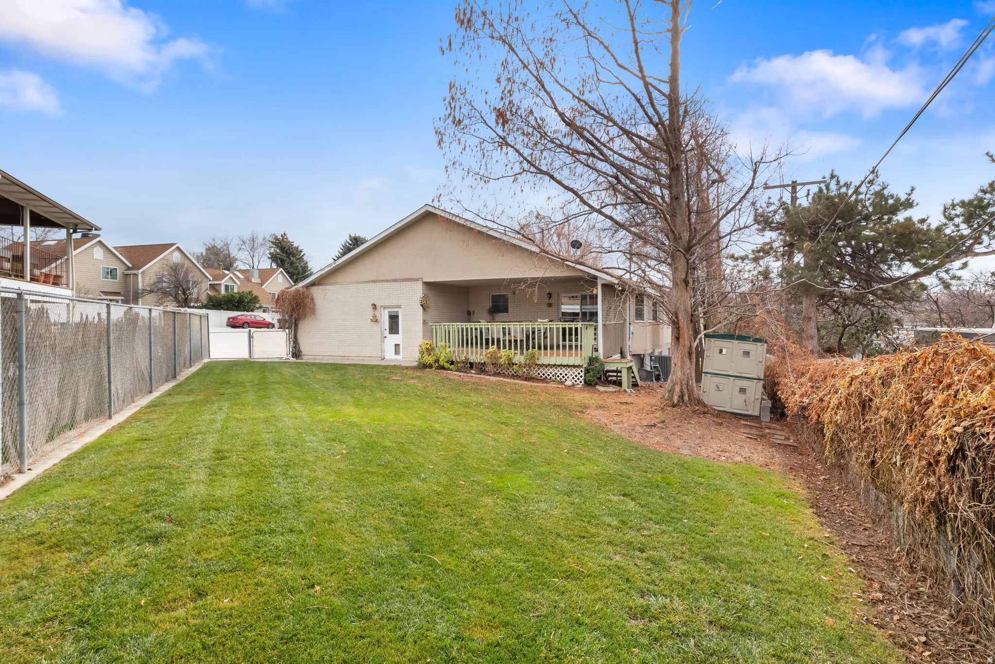 Back of house with a fenced backyard, brick siding, and a storage unit