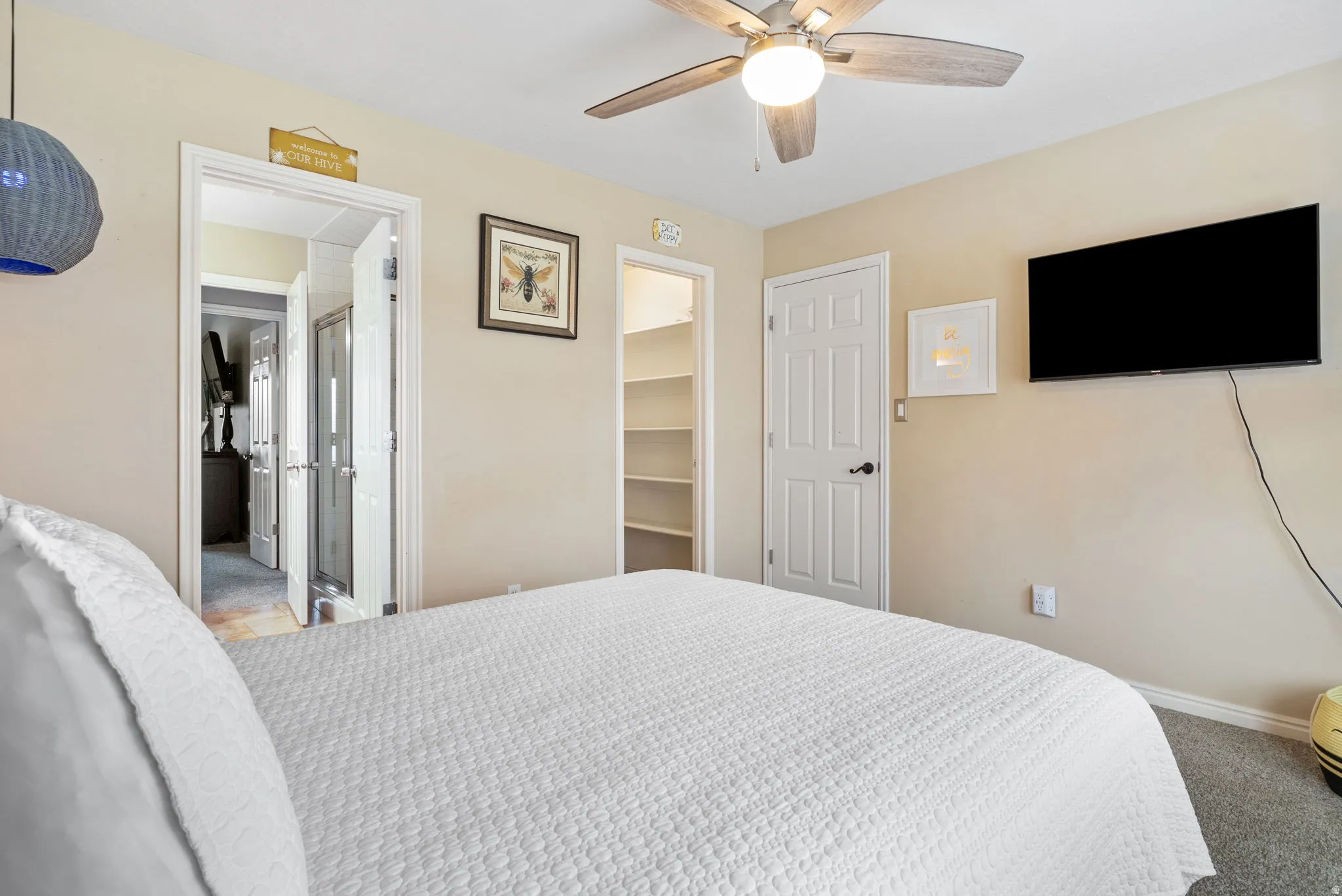 Bedroom featuring a walk in closet, carpet, and ceiling fan
