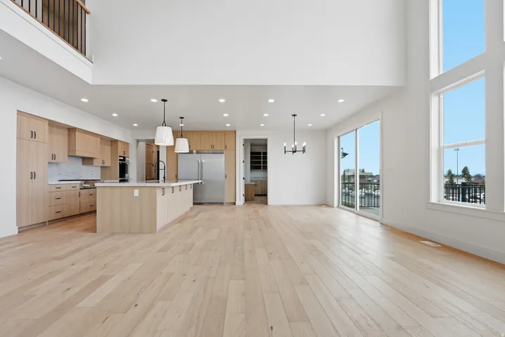 Kitchen featuring open floor plan, a center island with sink, modern cabinets, stainless steel appliances, and suspended lighting