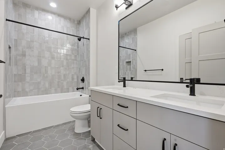 Bathroom with double vanity, shower / bathtub combination, light tile patterned floors, and recessed lighting
