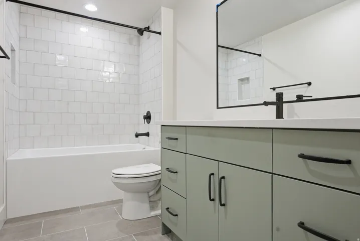 Bathroom featuring vanity,  shower combination, light tile patterned flooring, and recessed lighting