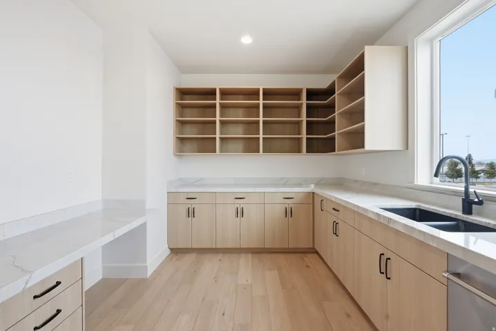 Kitchen featuring light wood finish cabinetry, light wood-style floors, open shelves, light stone countertops, and recessed lighting