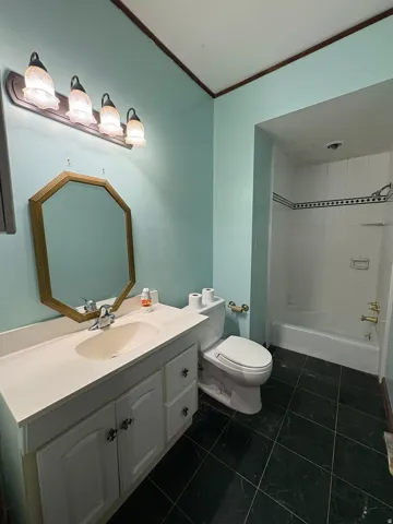 Bathroom vanity with a built-in sink, an octagonal framed mirror, and a four-light fixture