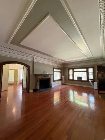 Spacious interior featuring wood-finish flooring and a decorative fireplace with a stone hearth
