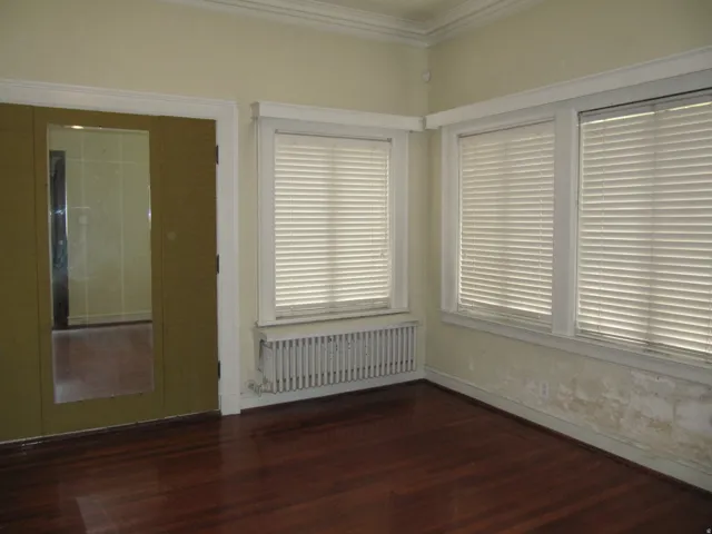 Bedroom with radiator, dark wood-type flooring, and crown molding