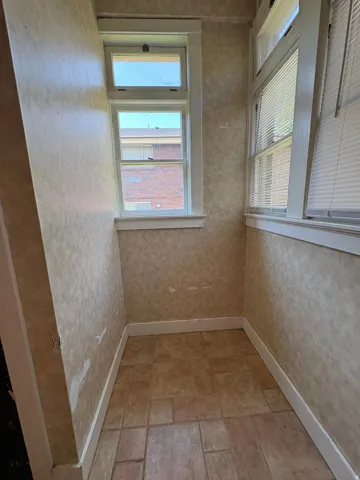 Compact space featuring patterned wallpaper, white trim, and tiled flooring