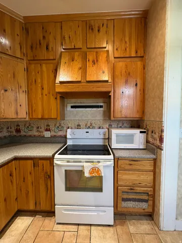 Kitchen featuring wood cabinetry, speckled countertops, and an electric range