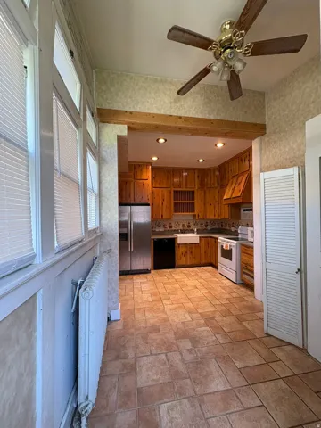 Spacious kitchen area featuring warm wood cabinetry, stainless steel refrigerator, white farmhouse sink, and recessed lighting