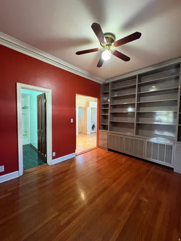 Hardwood flooring throughout featuring an integrated ceiling fan with lighting, built-in shelving, and crown molding