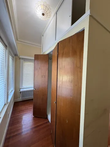 Room featuring wood-finish flooring, two sets of double-door cabinetry, and an ornate flush-mount ceiling fixture