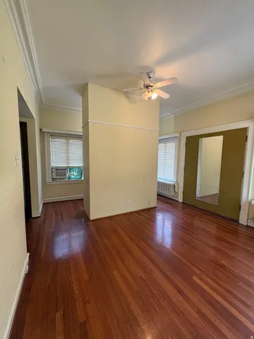 Spacious interior featuring wood-finish flooring, crown molding, and a ceiling fan with integrated lighting