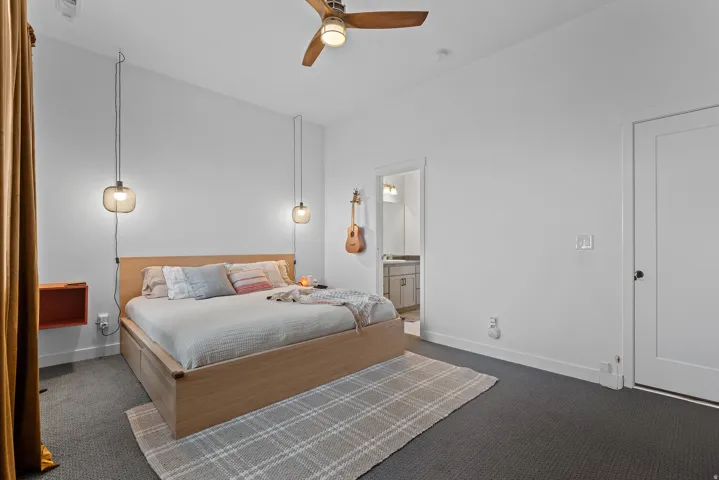 Bedroom featuring ceiling fan, carpet, and ensuite bathroom