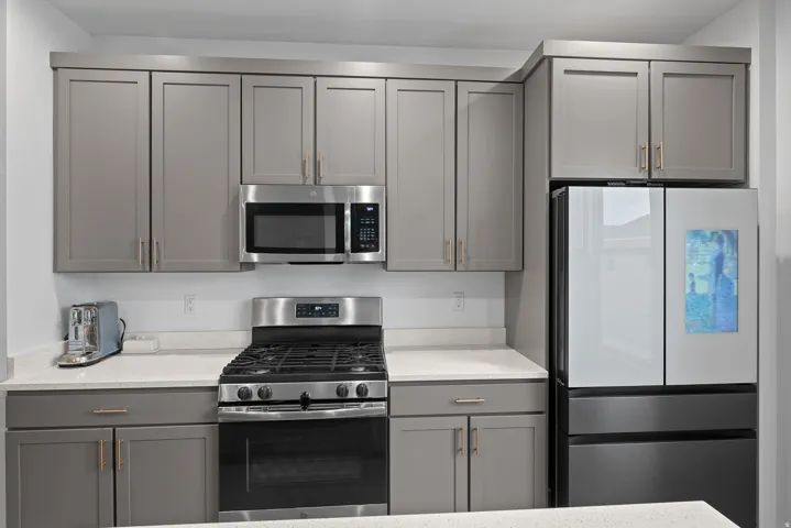 Kitchen featuring gray cabinets, appliances with stainless steel finishes, and light stone countertops