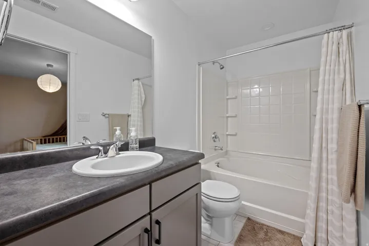 Bathroom featuring shower / bathtub combination with curtain, vanity, and light tile patterned floors