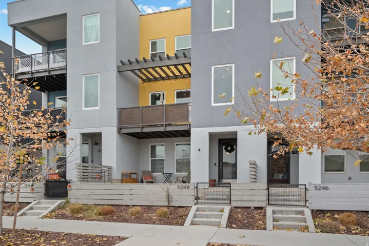 Contemporary house featuring stucco siding, a fenced front yard, a balcony, and a gate