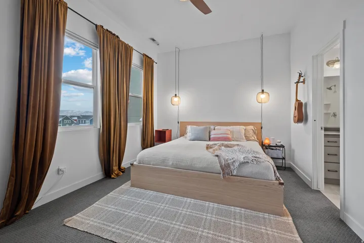 Carpeted bedroom with ceiling fan and ensuite bath
