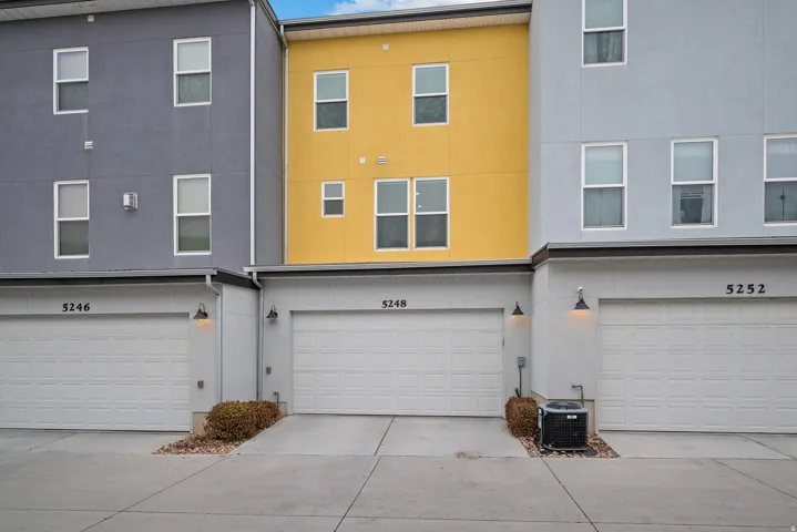 Back of property featuring concrete driveway, stucco siding, and an attached garage