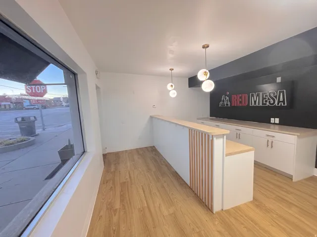 Bar area with light countertops, pendant lighting, white cabinets, and light wood finished floors
