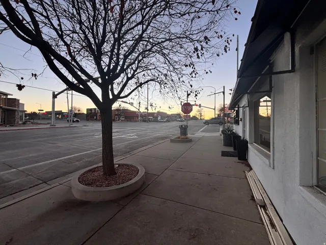 View of asphalt street featuring sidewalks, curbs, and street lights