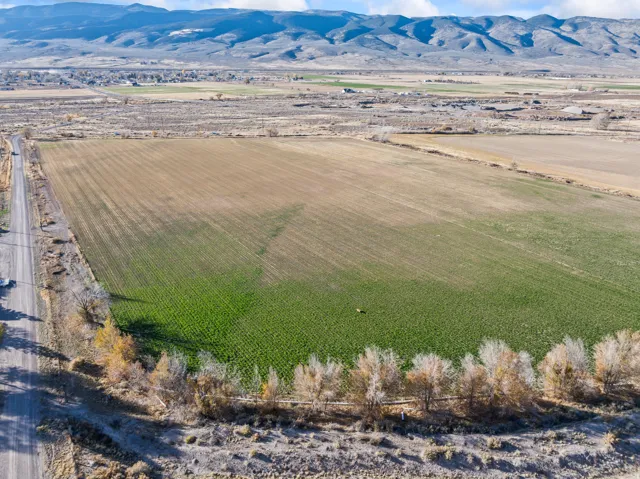Aerial view of sparsely populated area featuring large plots for crops and a mountainous background