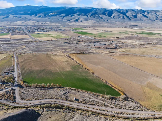 Aerial view of sparsely populated area featuring a mountainous background and extensive farmland