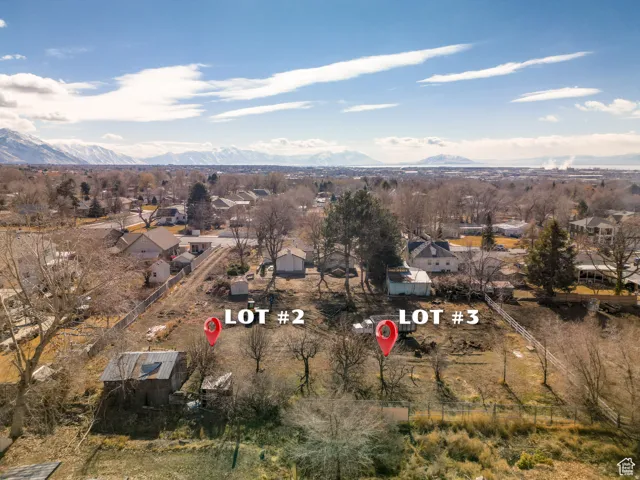 Aerial view of property and surrounding area featuring nearby suburban area and a mountain backdrop