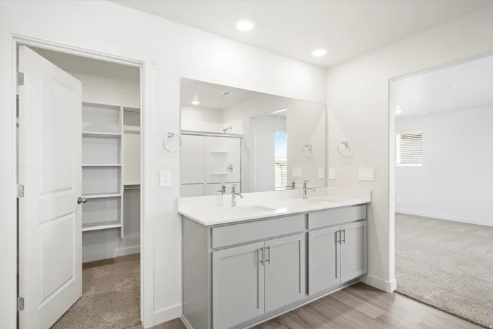 ***DISCLAIMER** Exterior & Interior finishes may vary. Bathroom with double vanity, light carpet, a walk in closet, and a stall shower