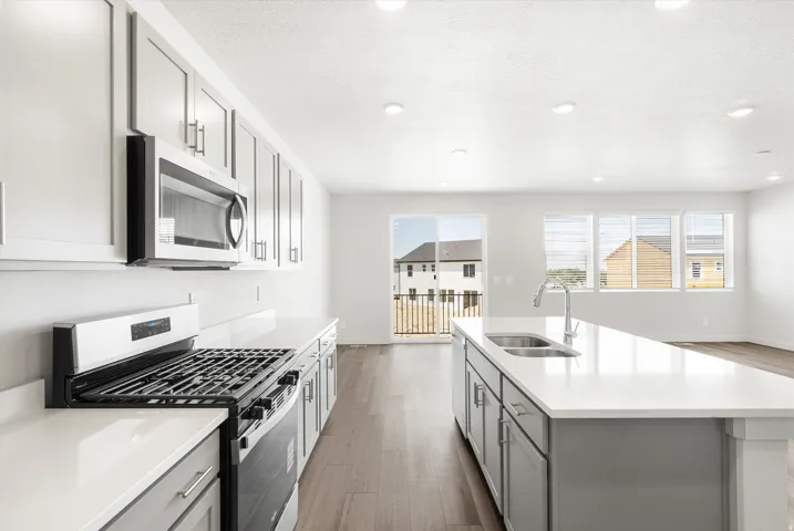 ***DISCLAIMER** Exterior & Interior finishes may vary. Kitchen with gray cabinets, appliances with stainless steel finishes, dark wood-style floors, a kitchen island with sink, and recessed lighting