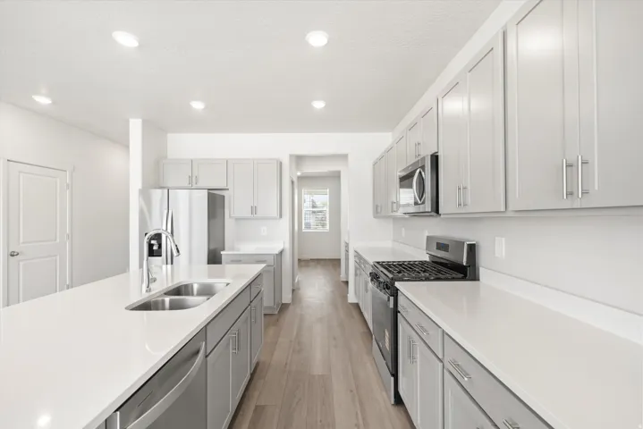 ***DISCLAIMER** Exterior & Interior finishes may vary. Kitchen with appliances with stainless steel finishes, recessed lighting, light wood-type flooring, gray cabinets, and light stone countertops