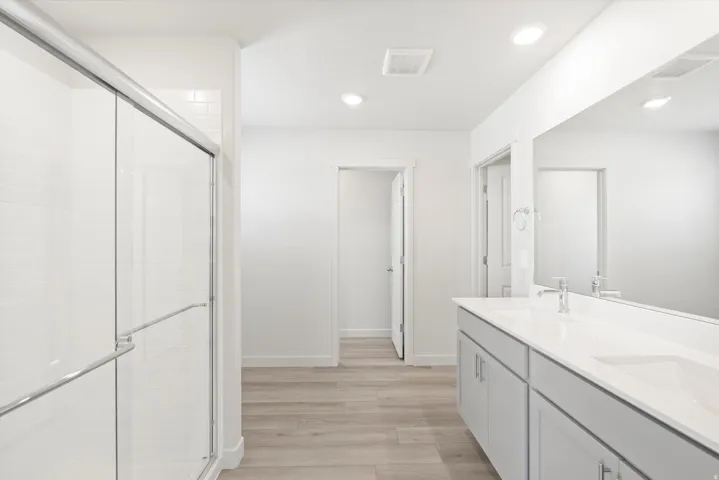 ***DISCLAIMER** Exterior & Interior finishes may vary. Bathroom with double vanity, light wood finished floors, a stall shower, and recessed lighting