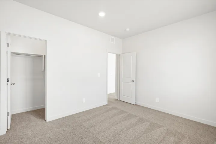 ***DISCLAIMER** Exterior & Interior finishes may vary. Unfurnished bedroom featuring light colored carpet and a walk in closet