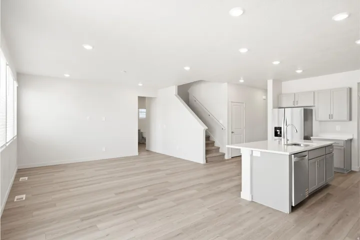 ***DISCLAIMER** Exterior & Interior finishes may vary. Kitchen with gray cabinetry, a center island with sink, light wood-style floors, appliances with stainless steel finishes, and recessed lighting