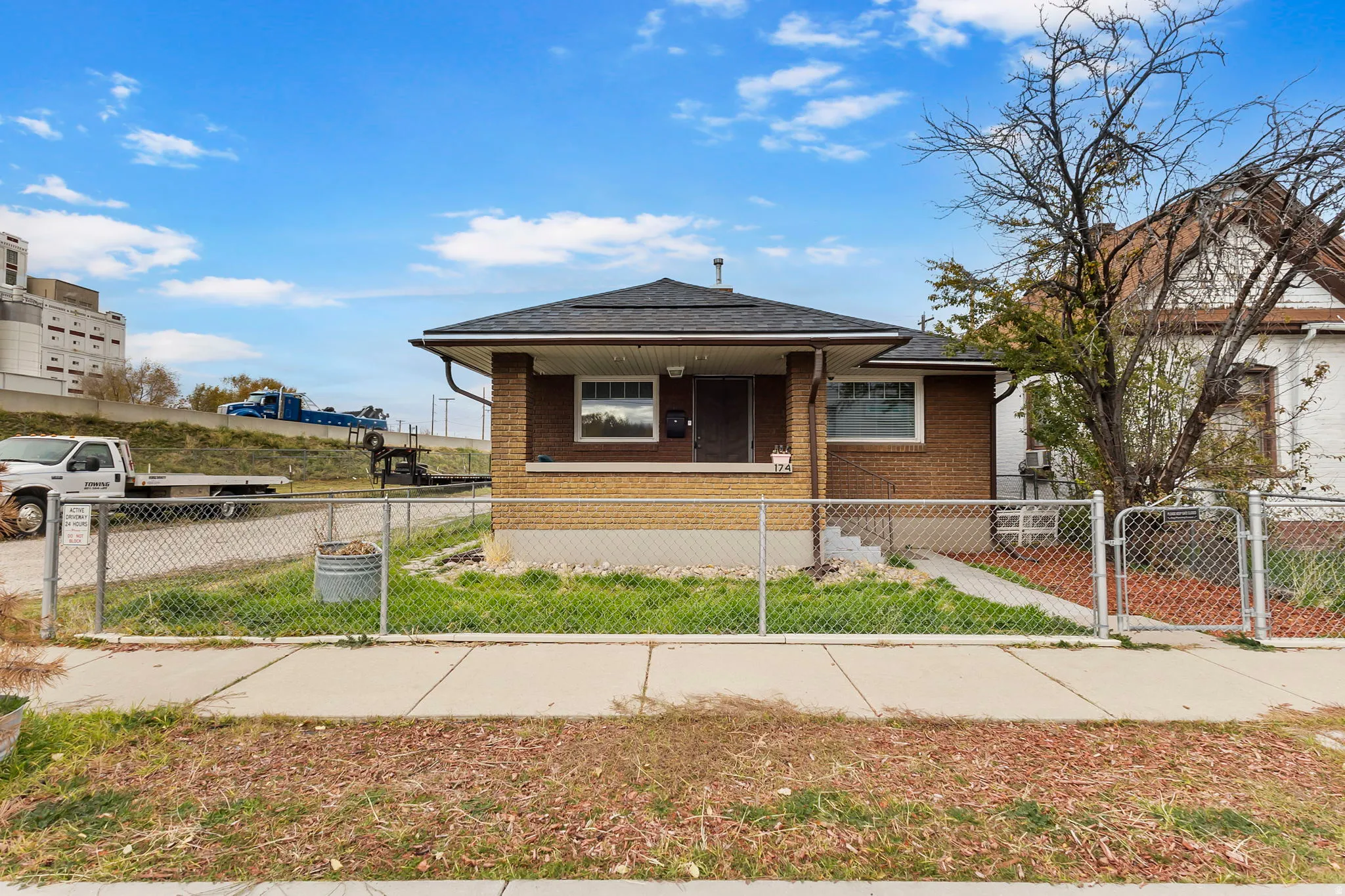 Bungalow-style home with a gate, a fenced front yard, covered porch, and brick siding