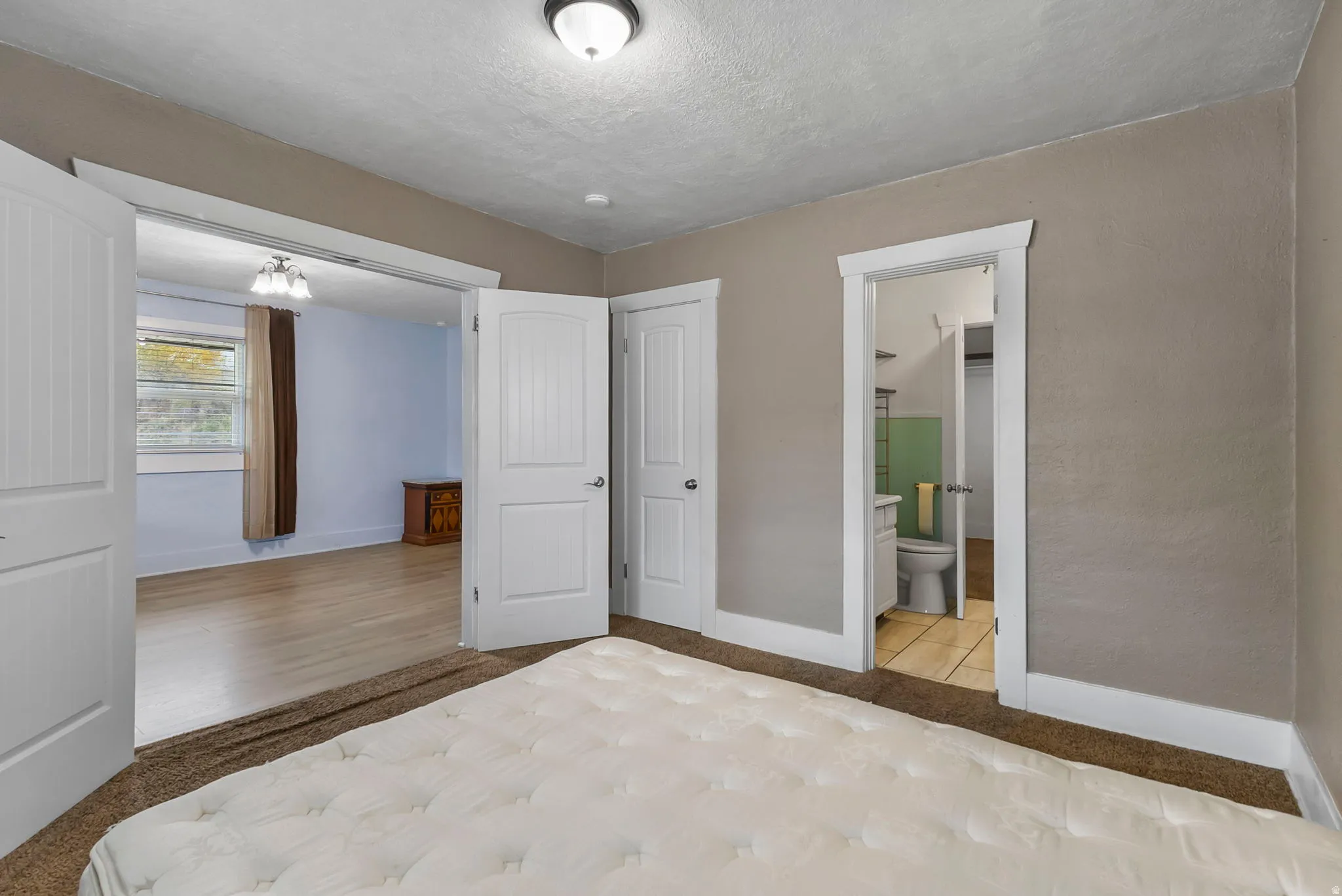 Unfurnished bedroom with a textured ceiling and connected bathroom