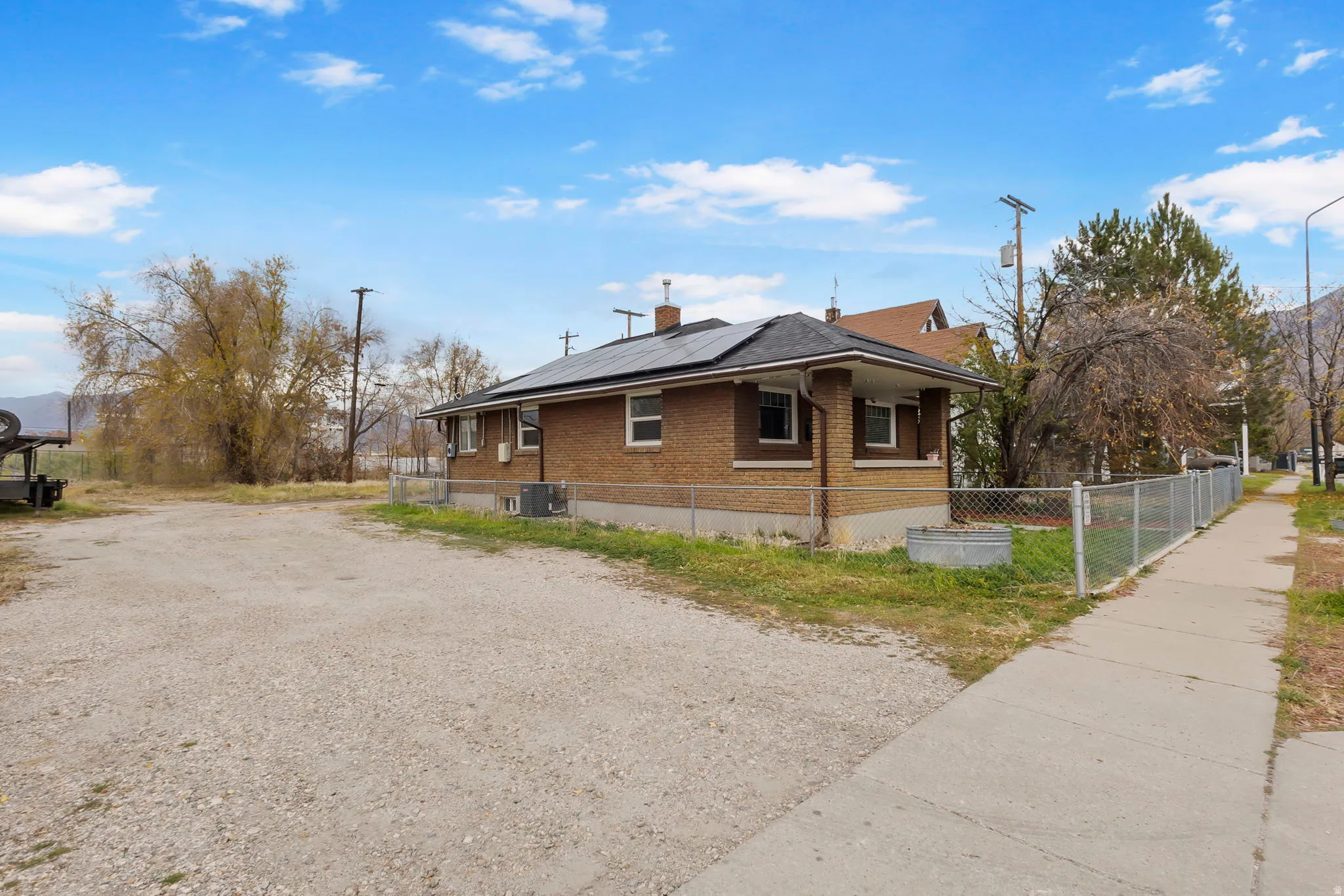 View of property exterior featuring roof mounted solar panels, brick siding, a chimney, and driveway