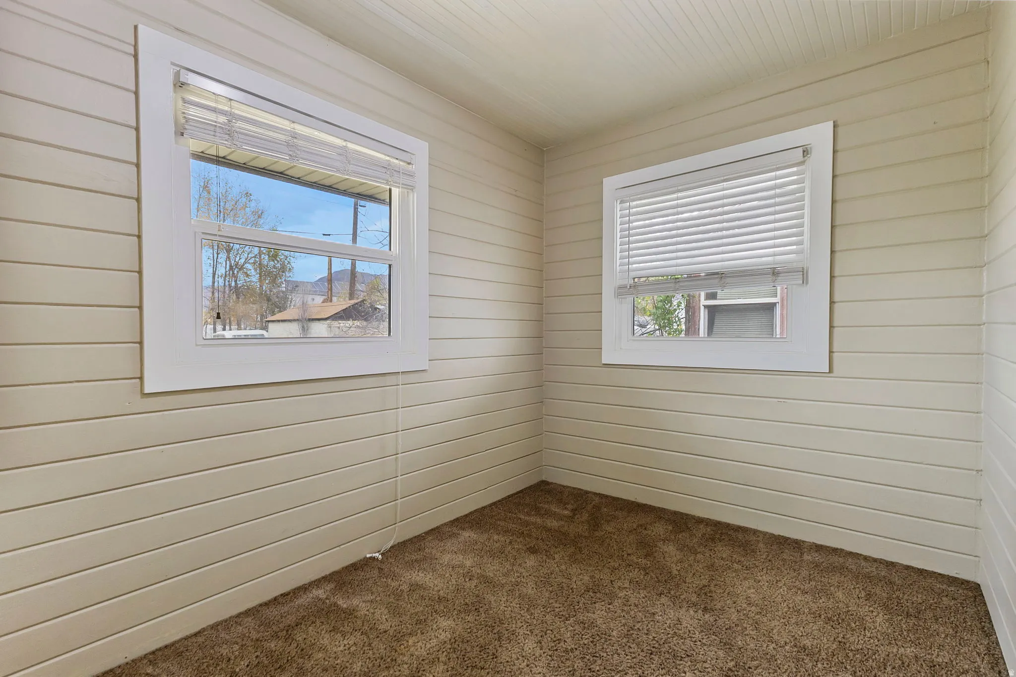 Spare room with dark carpet and wood walls
