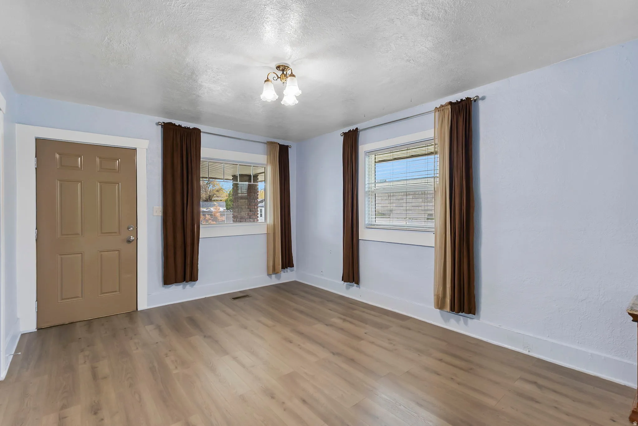 Empty room featuring a textured ceiling, wood finished floors, and a chandelier