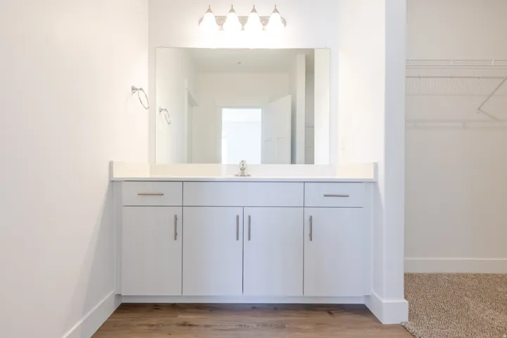 Bathroom vanity featuring a single sink, light-colored countertop, and white cabinetry with brushed nickel hardware