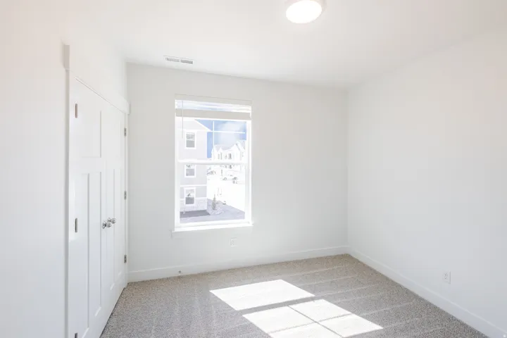 Bright room featuring a flush-mount ceiling light, white walls, and neutral-toned carpeting