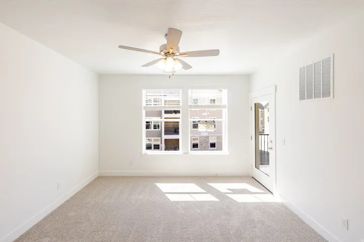 Room with light beige carpet, white walls, and a ceiling fan