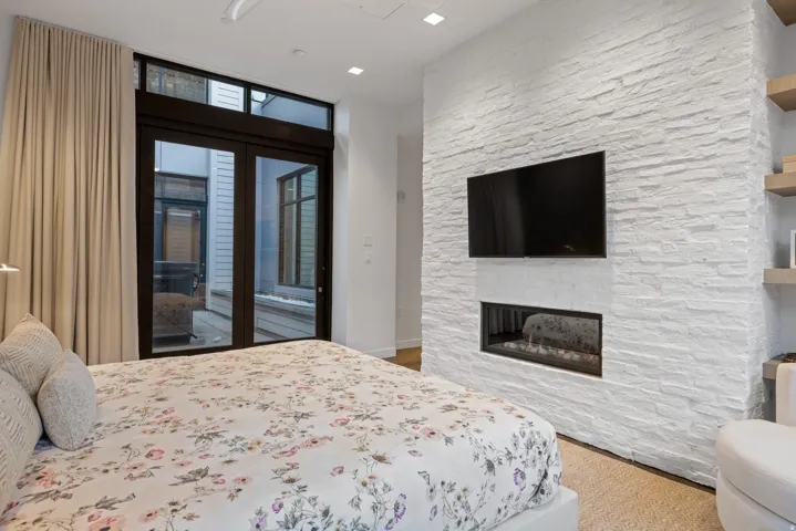 Bedroom with access to outside and a stone fireplace