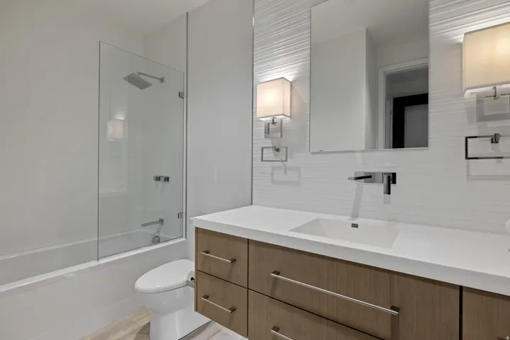 Bathroom with vanity, shower / bathtub combination, and tasteful backsplash