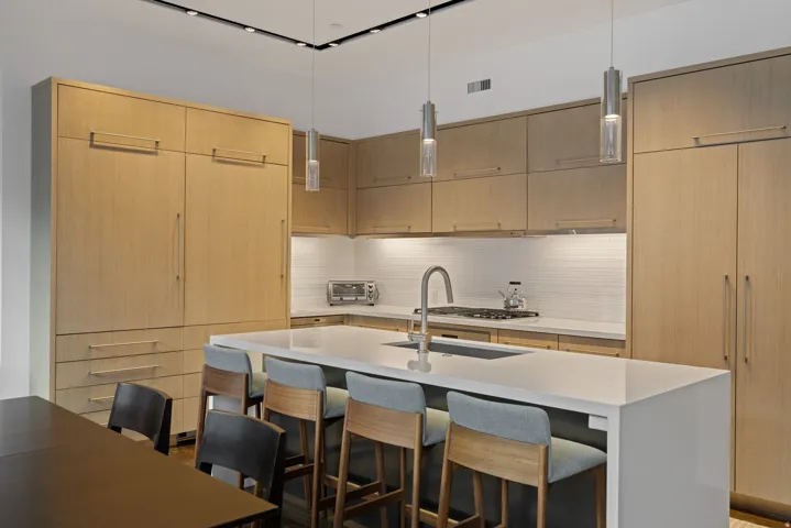 Kitchen with modern cabinets, a breakfast bar, pendant lighting, and light stone countertops